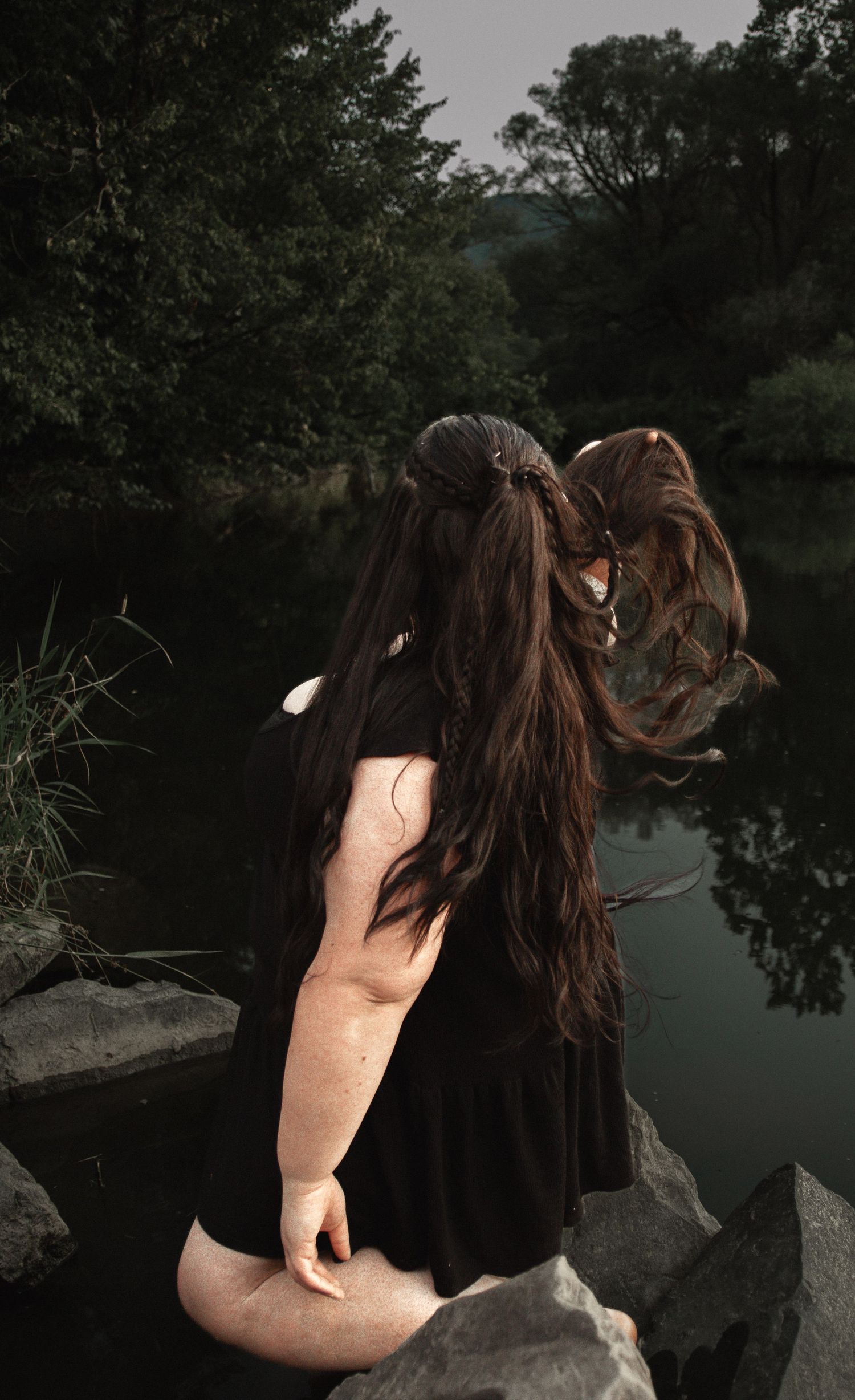 Dramatic lakeside portrait with long dark hair flowing in the breeze.