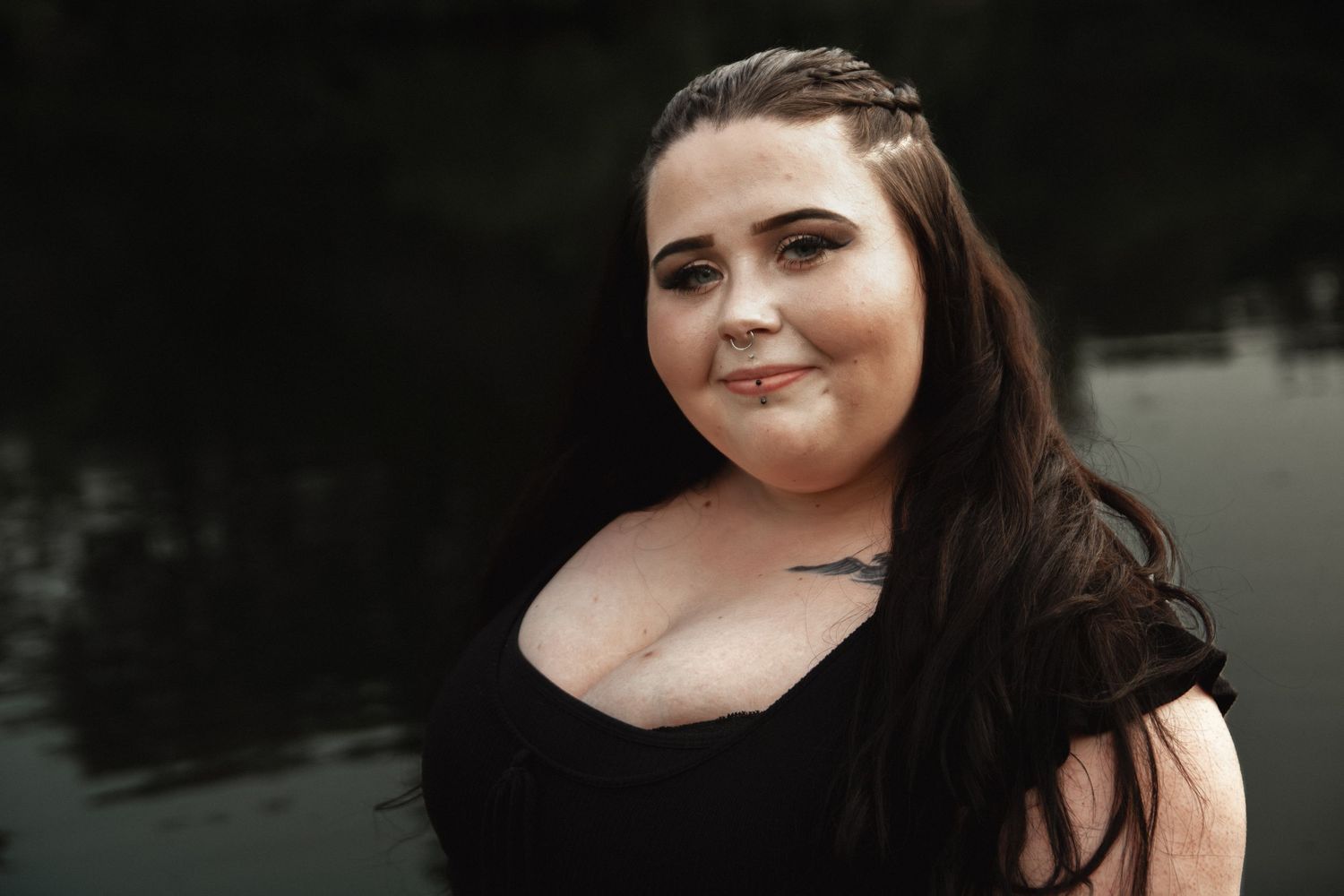 Outdoor portrait with braided hair detail against a serene lake background.