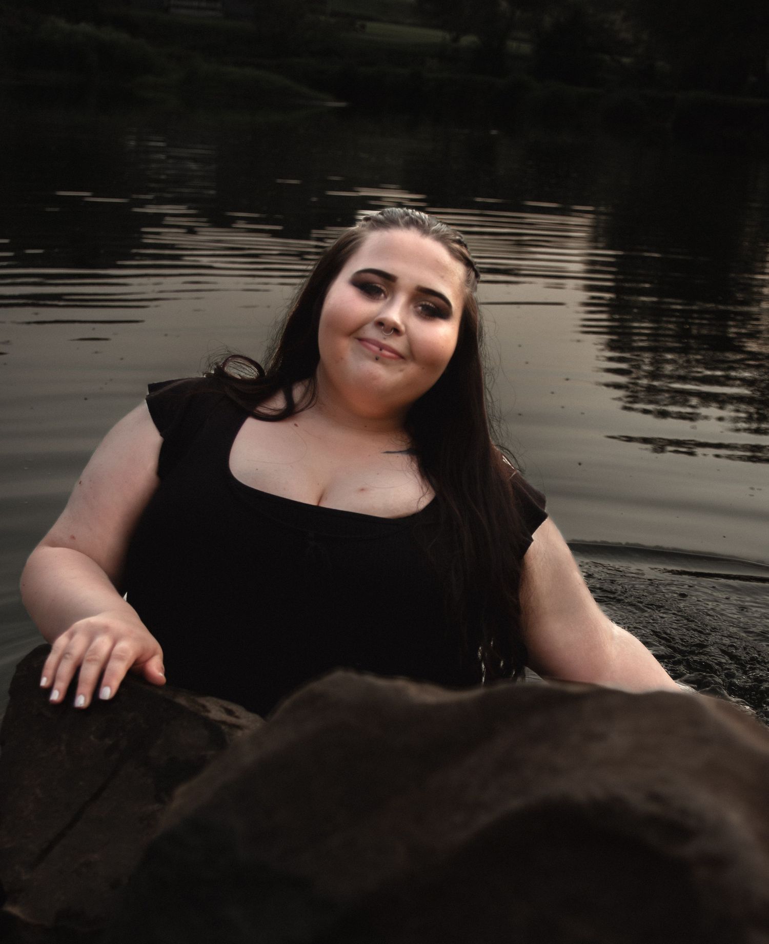 Lakeside portrait with natural lighting and rock formations.