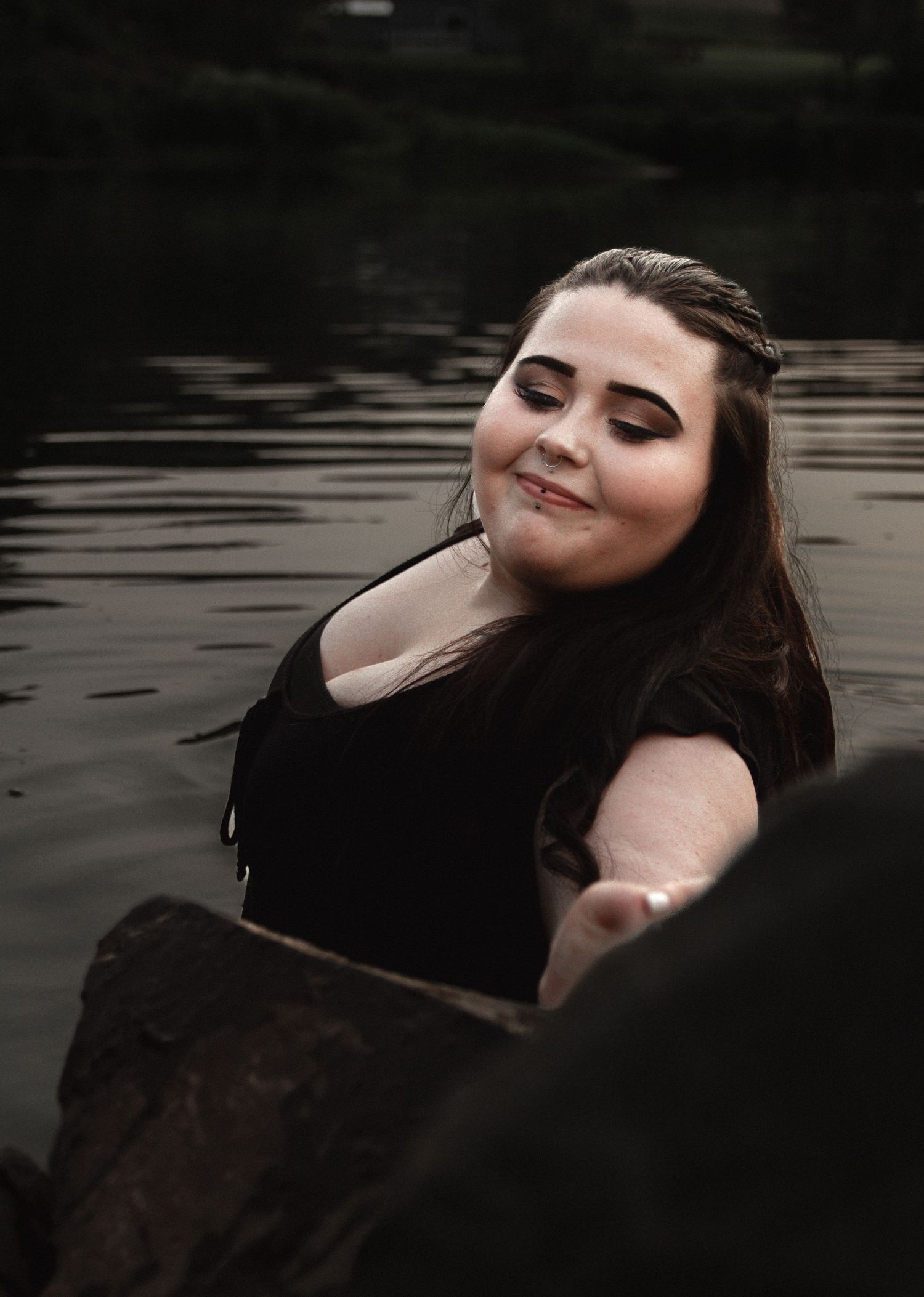 Serene waterside portrait with soft lighting and natural pose.