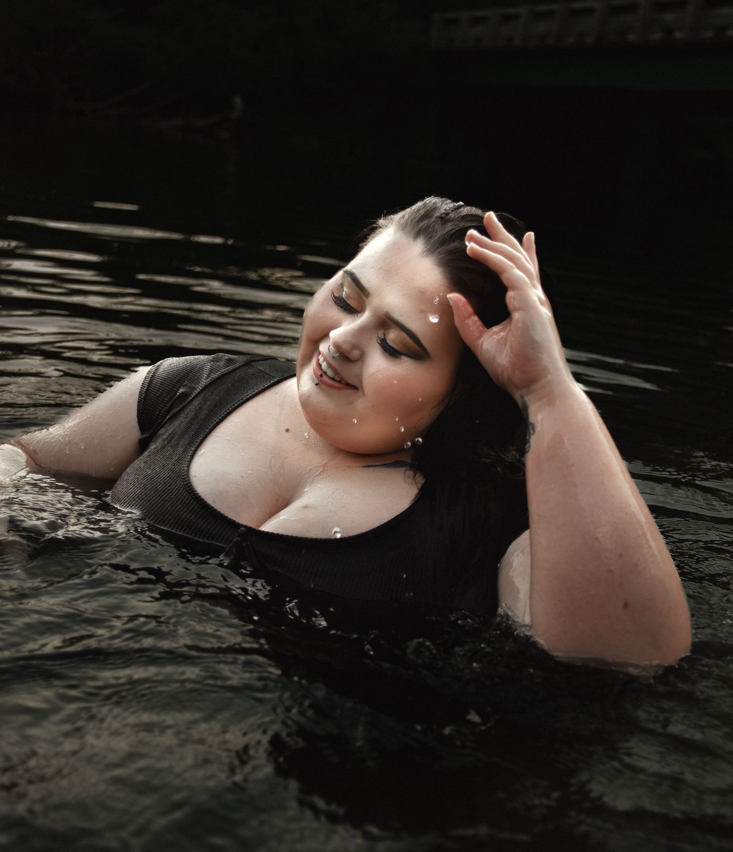 Dramatic water portrait with droplets and expressive pose in dark tones.