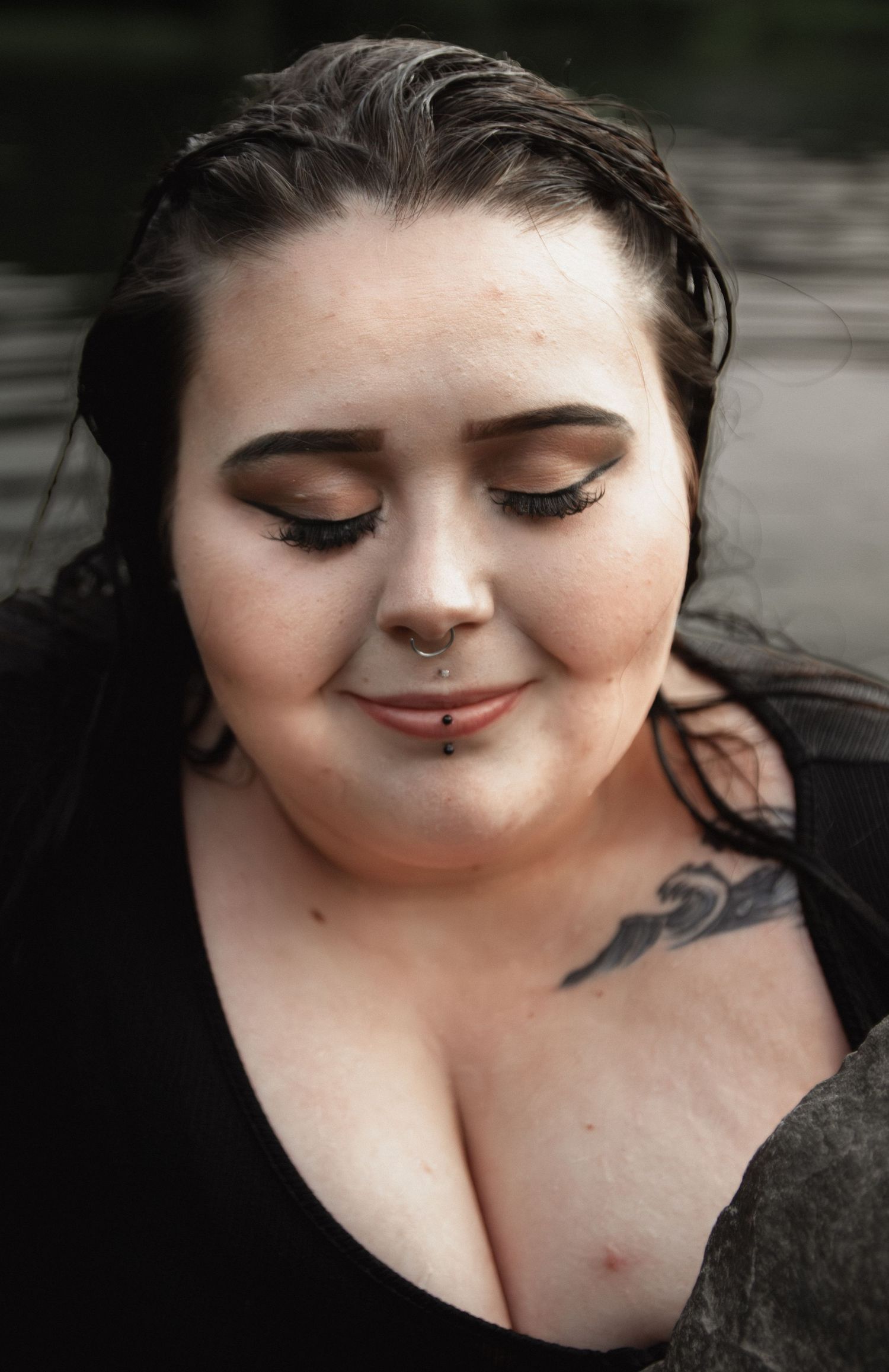 Intimate portrait showing nose piercing and closed-eye expression with wet hair.