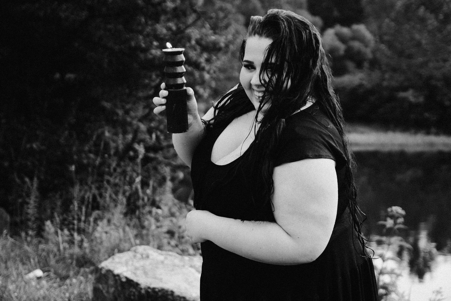 A joyful outdoor portrait session in black and white featuring a person holding a camera in nature.