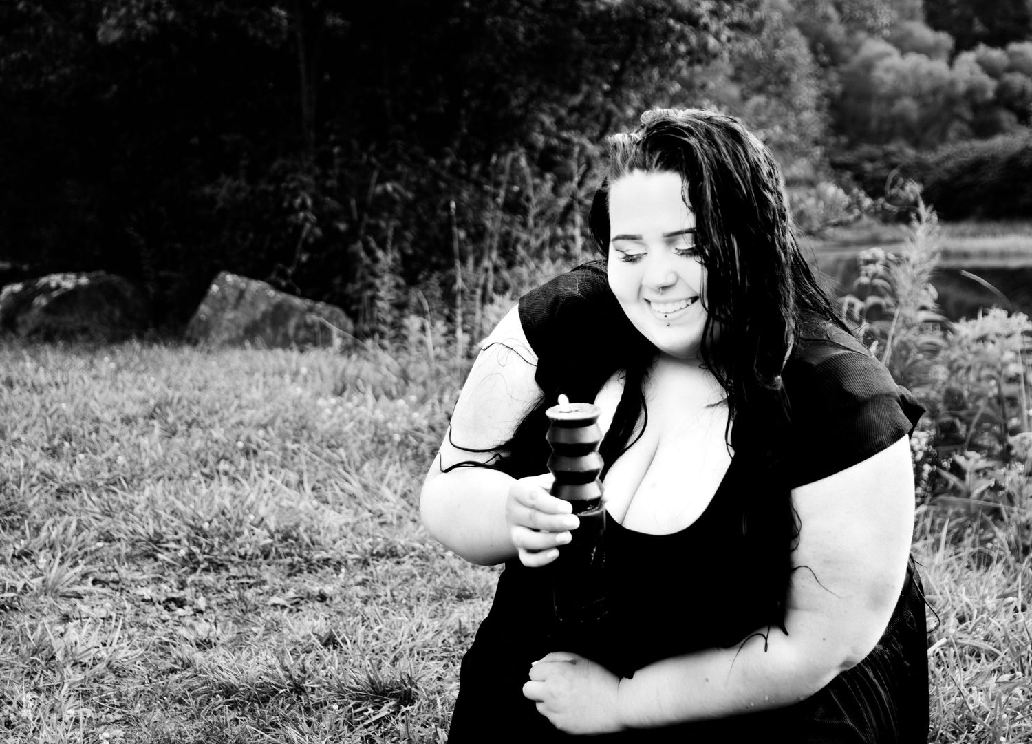 Black and white photo of someone laughing while holding a camera in a natural setting.