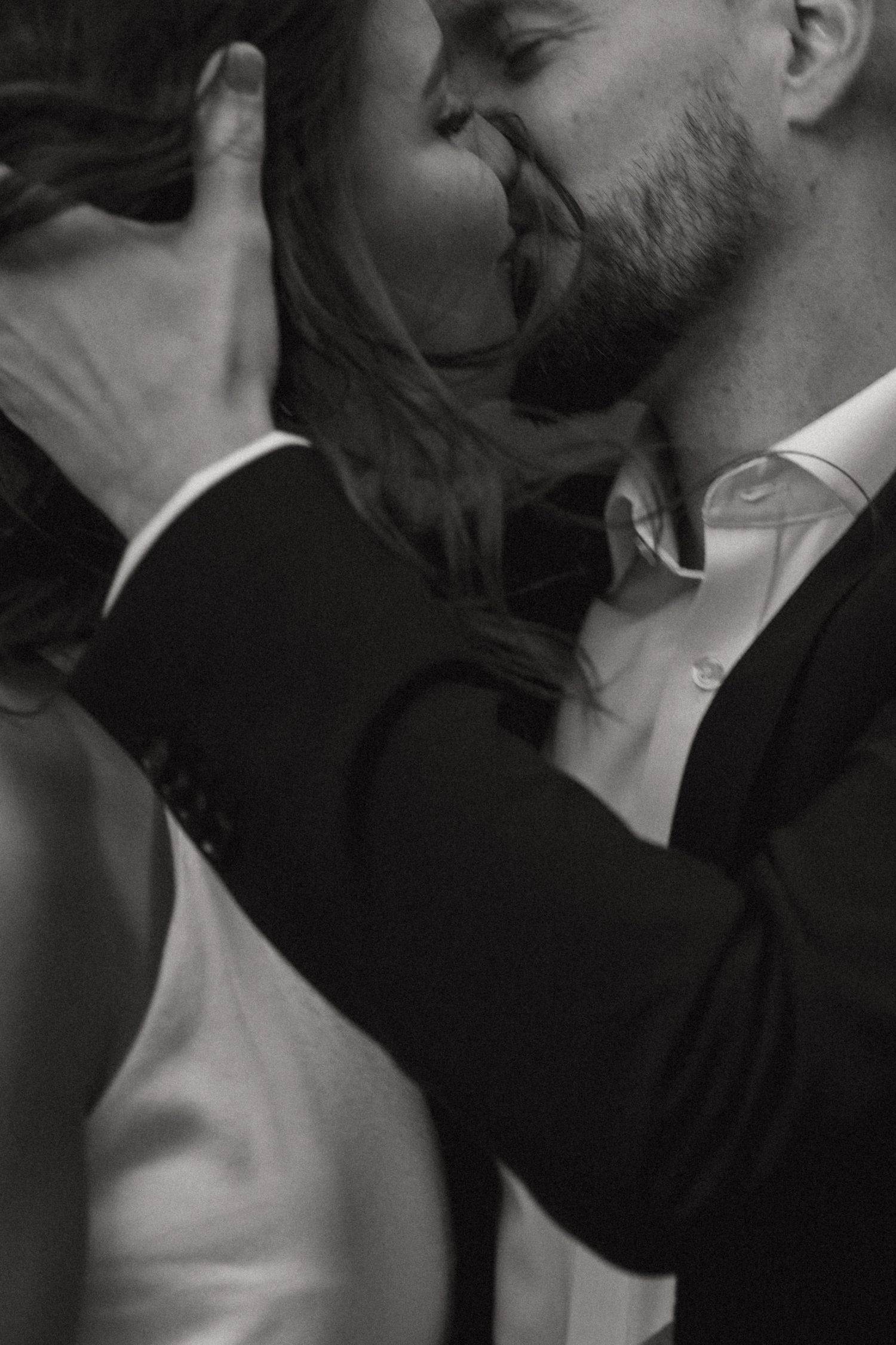 Intimate black and white photograph of a romantic couple in formal attire sharing a tender moment.