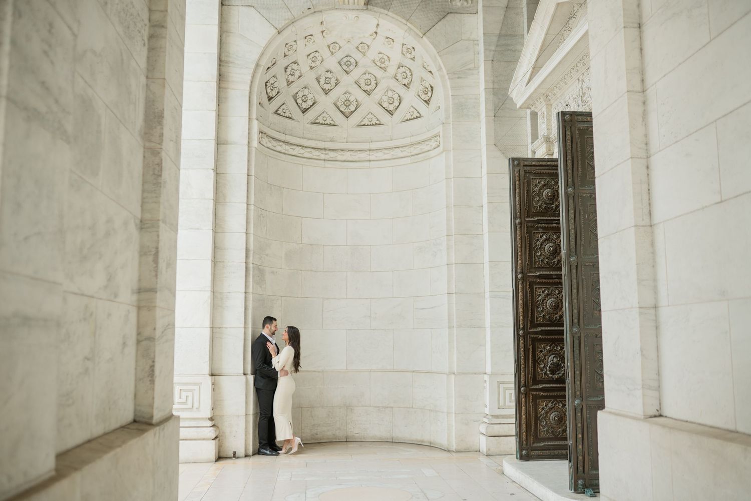 Interior of classical building with white stone columns and ornate domed ceiling details.