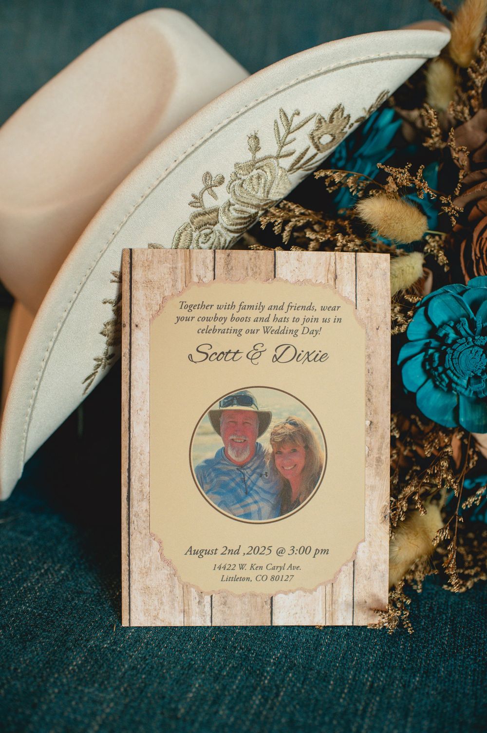 A vintage-style save the date wedding invitation card with floral details on a teal background.