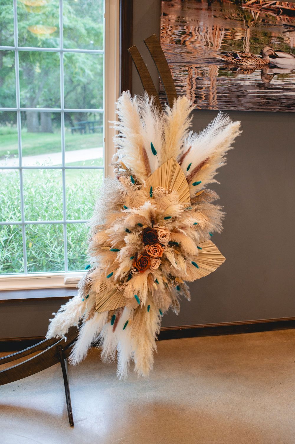 A trio of boho-style dried pampas grass and palm frond arrangements displayed in a modern interior space with window views.