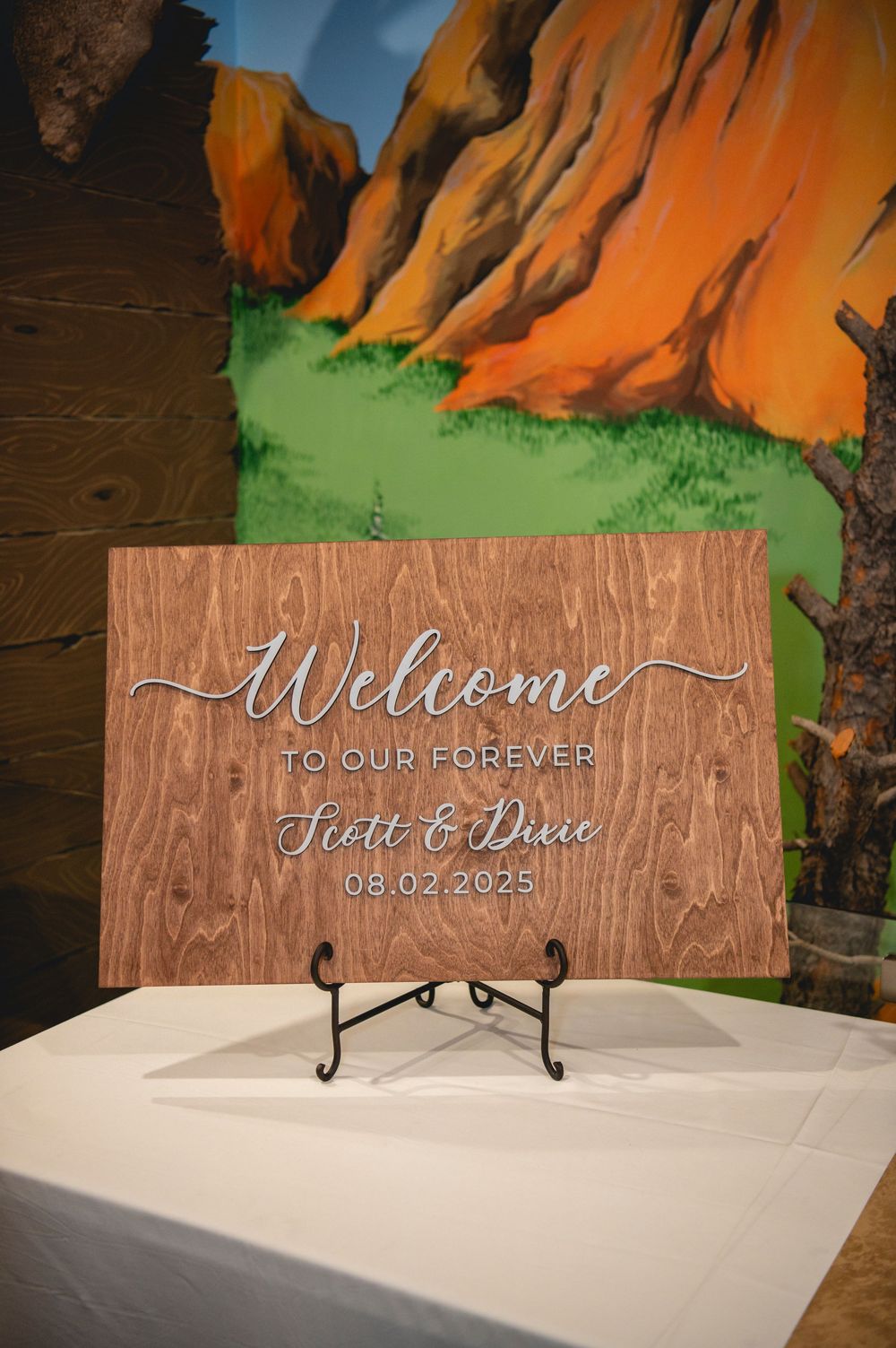 A sequence of wooden welcome signs with calligraphy text being photographed against an orange and green backdrop.