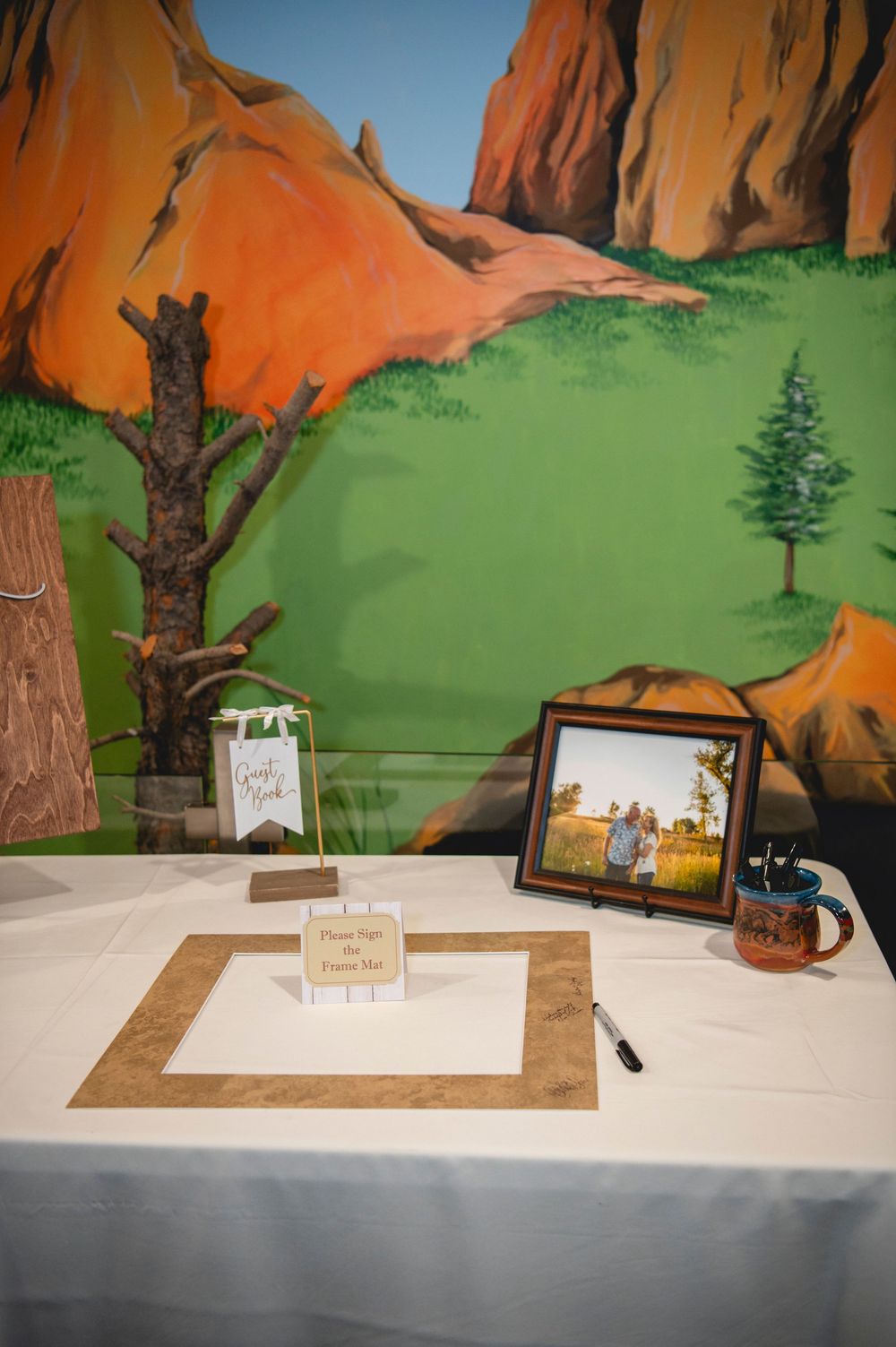 Guest book table setup at outdoor wedding venue with framed photo and rustic decor against red rock canyon backdrop.