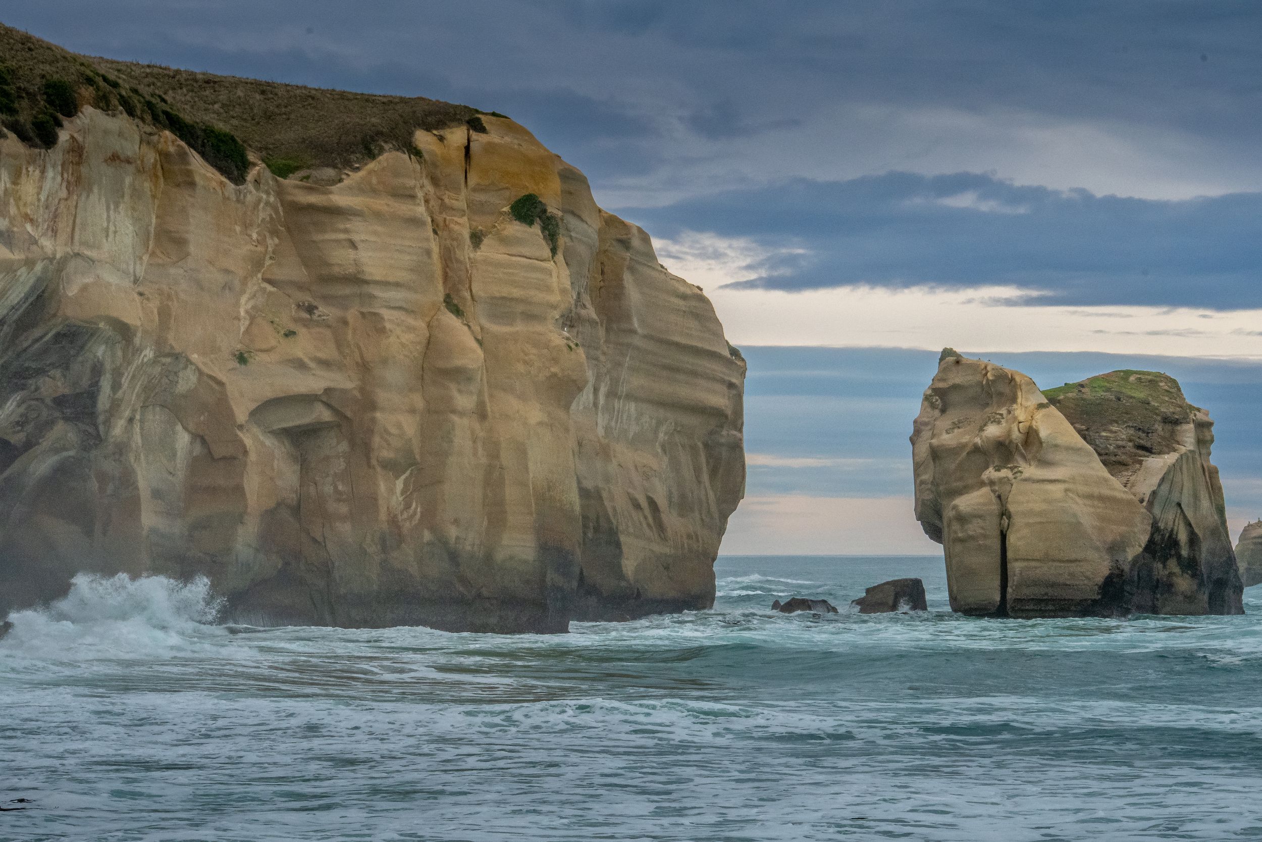 Falaises sculptées par l’érosion à Tunnel Beach, Nouvelle-Zélande, au bord de l’océan sous un ciel nuageux