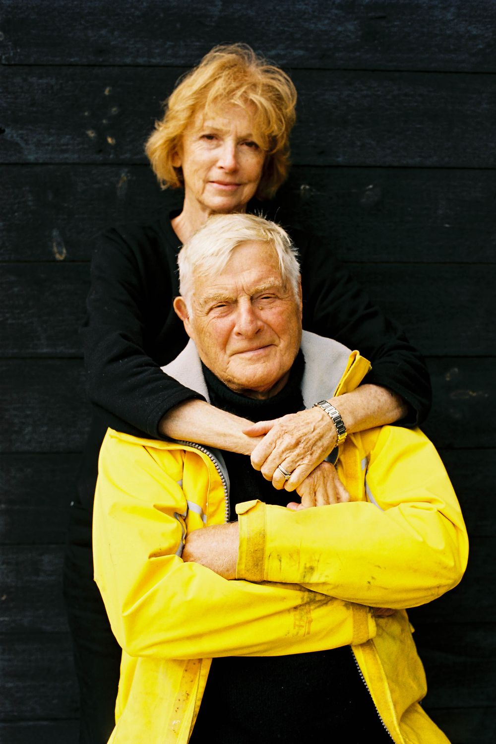 A mature couple embraces in front of their architectural home on an island near Rockland, Maine on 35mm film.