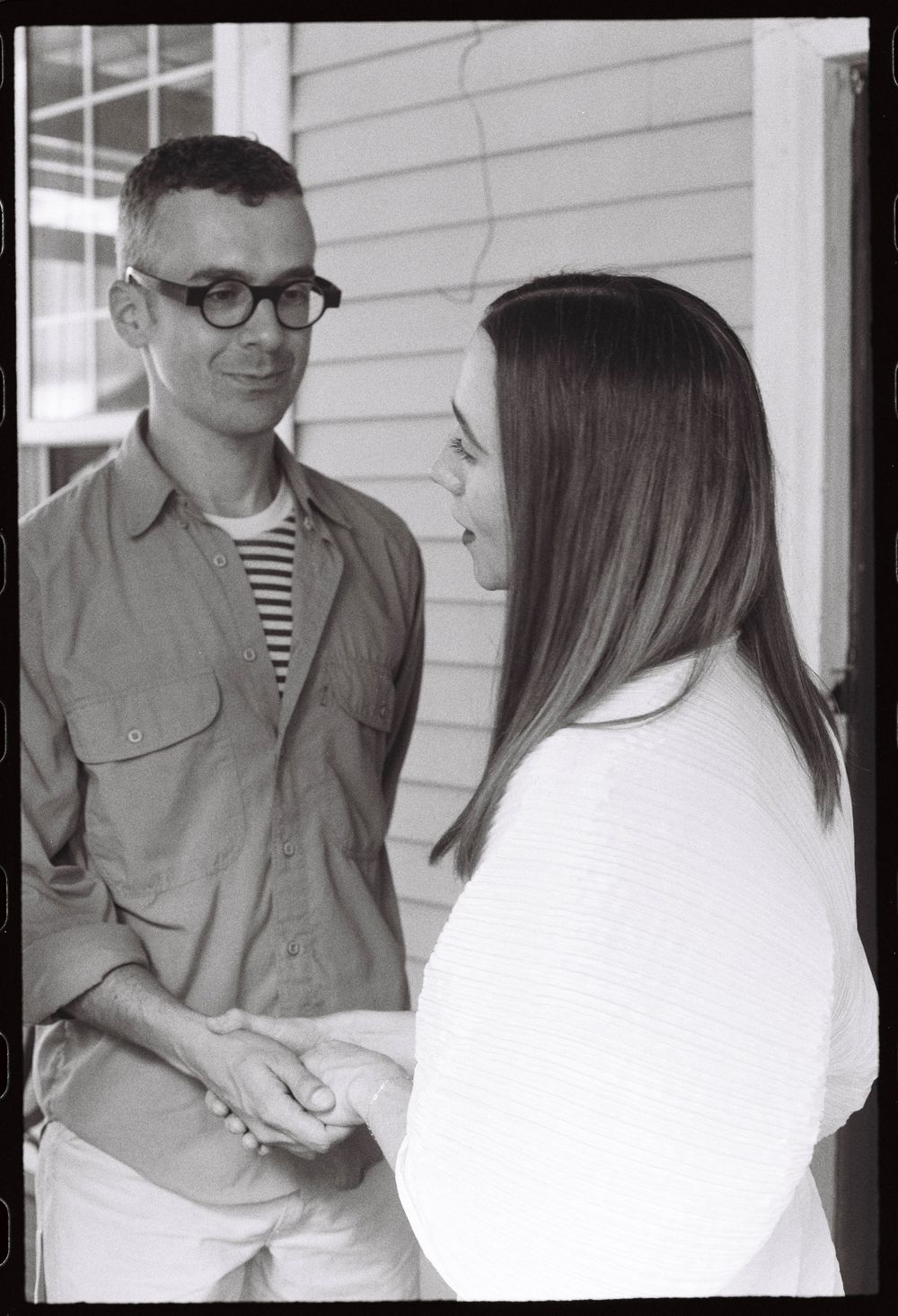 He holds her hand and looks at her lovingly during their engagement celebration party at a wine bar in the summer on film in Brunswick Maine