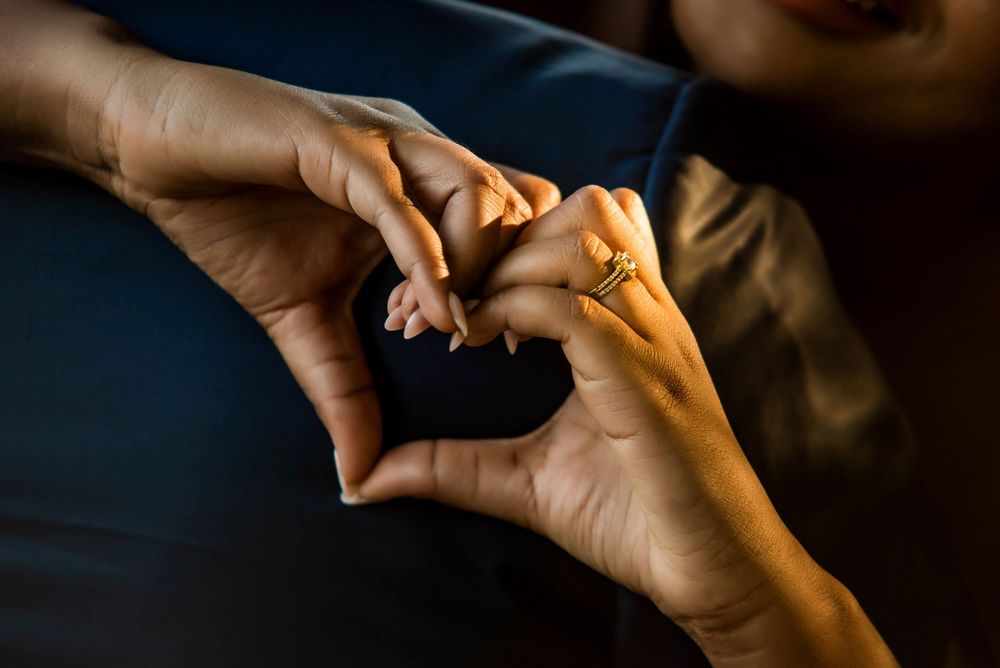 Two hands forming a heart shape against a dark background.