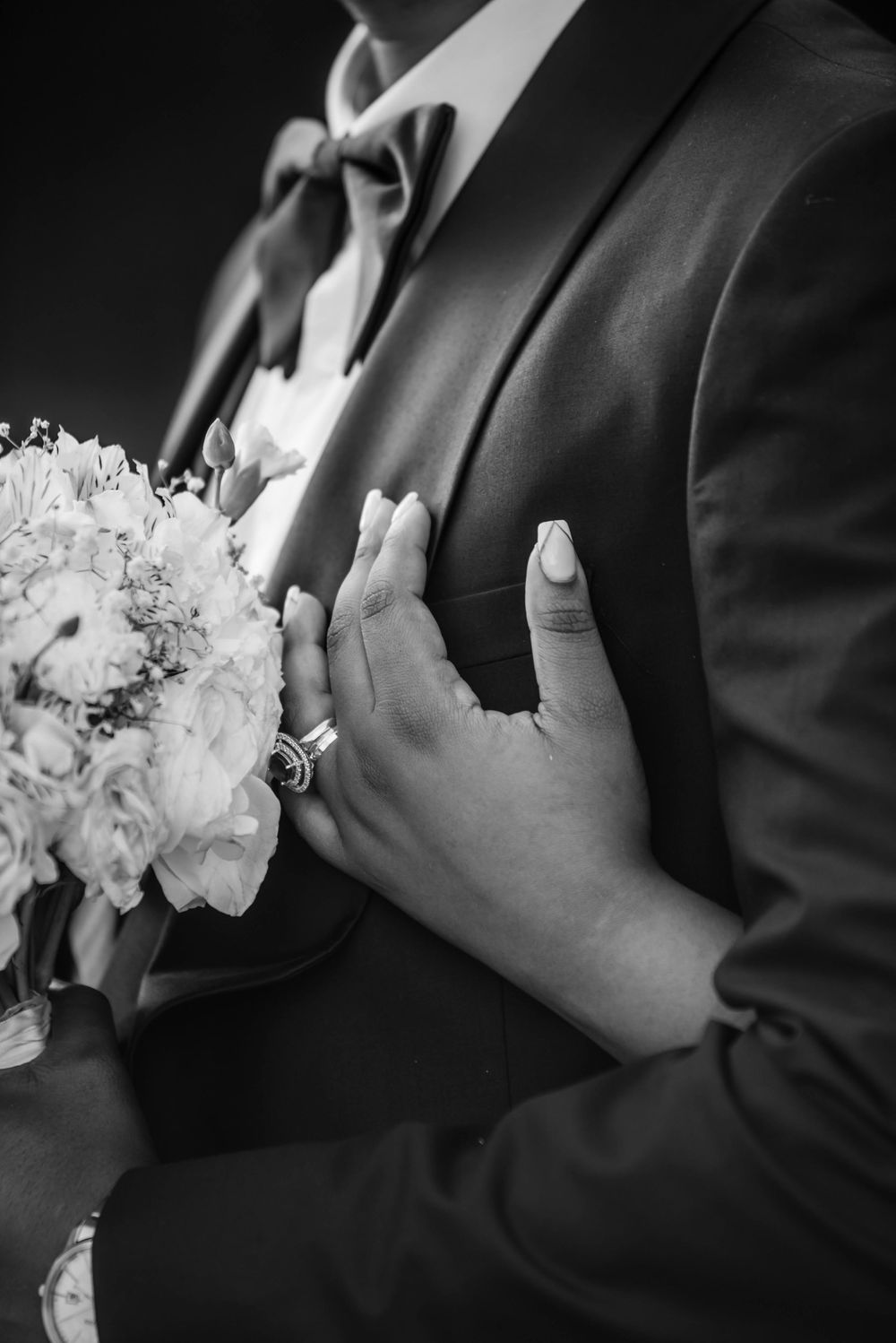 Black and white close-up of hands holding a white floral bouquet.