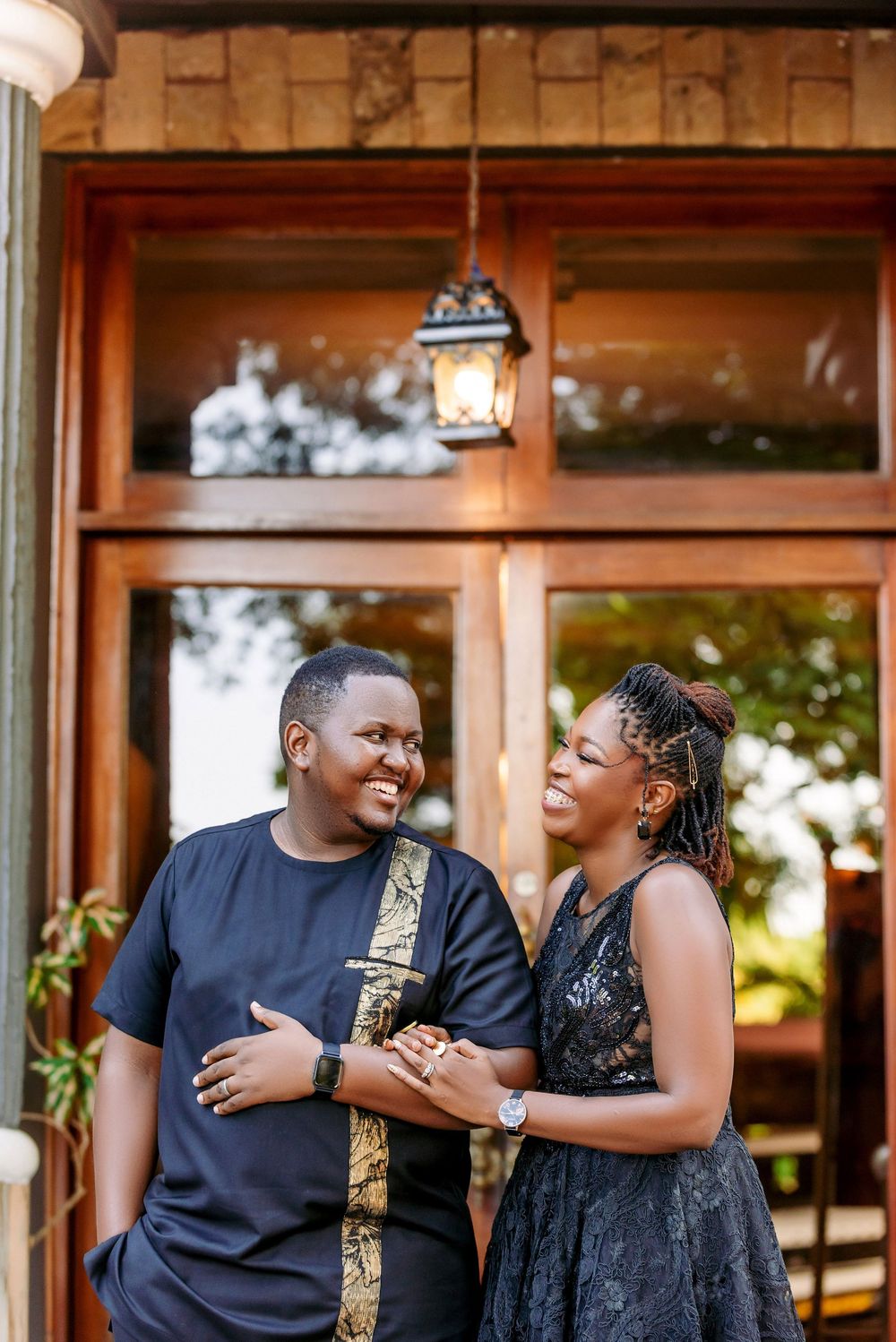 A couple shares a lighthearted moment outside a building with a vintage lantern.