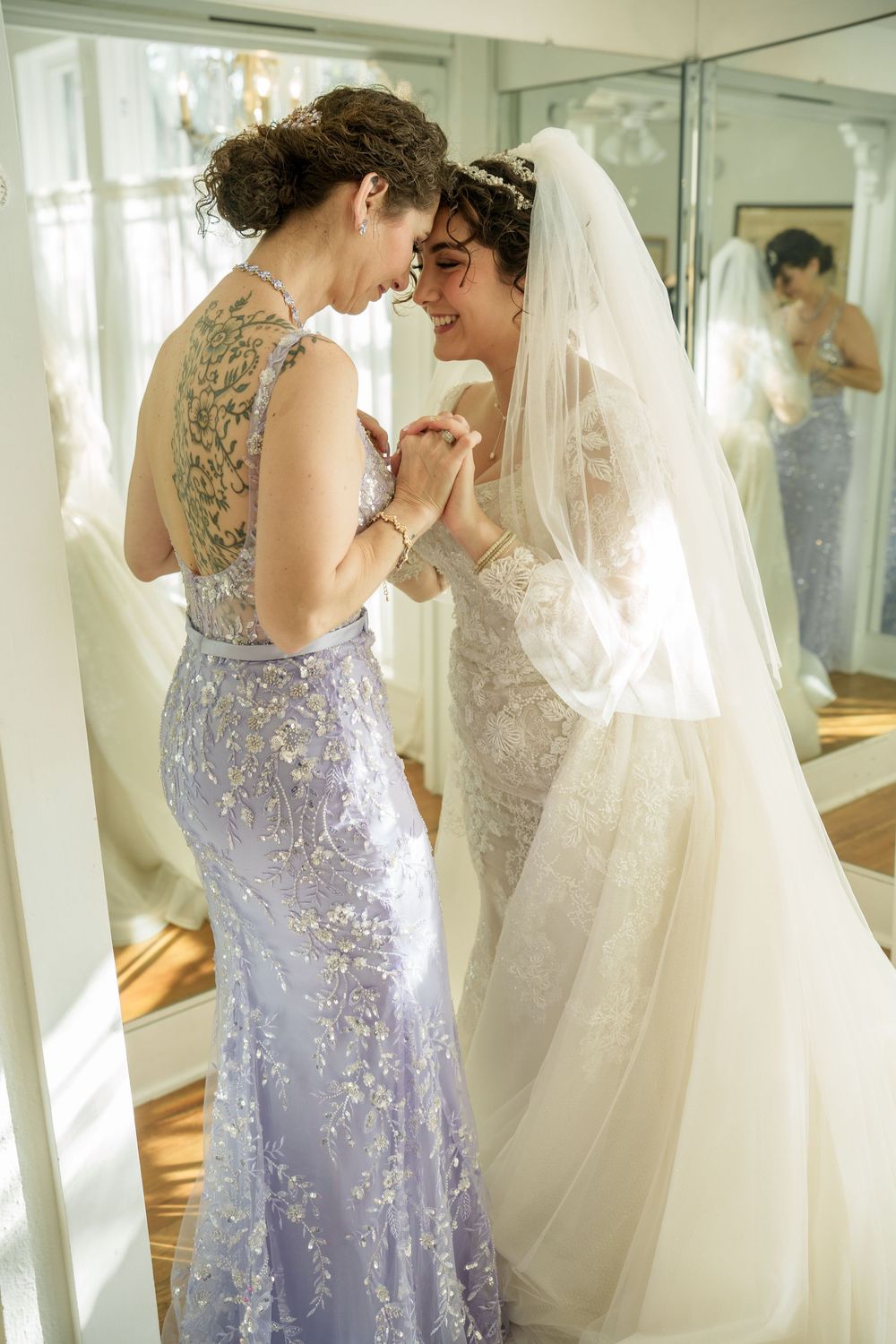 Wedding party in purple and white dresses preparing in a mirrored dressing room.