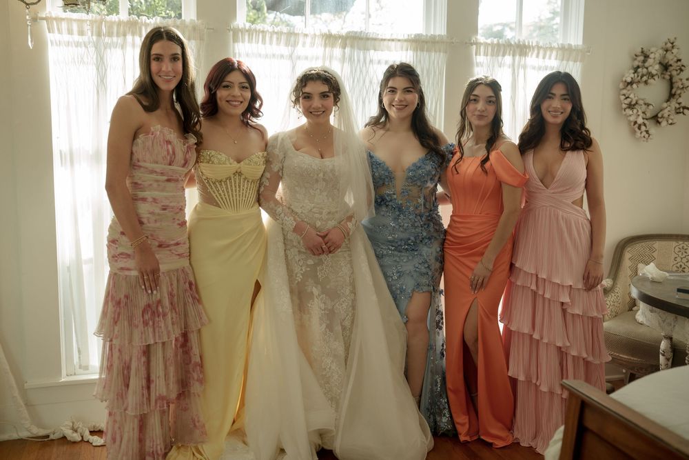 Wedding party in pastel bridesmaid dresses posing together indoors.