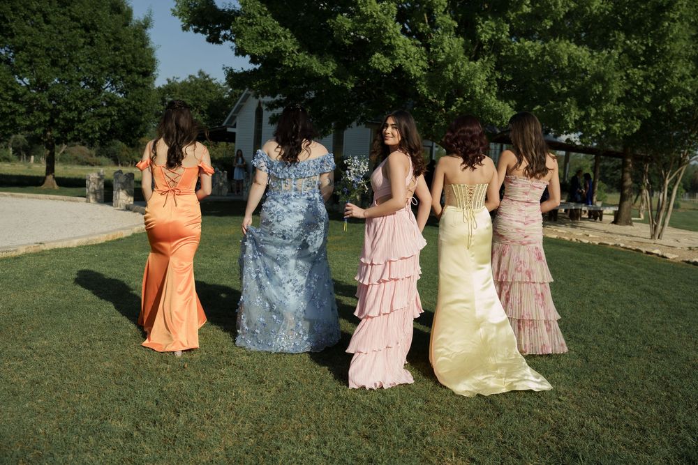 Bridesmaids in colorful dresses standing together on grass outdoors.