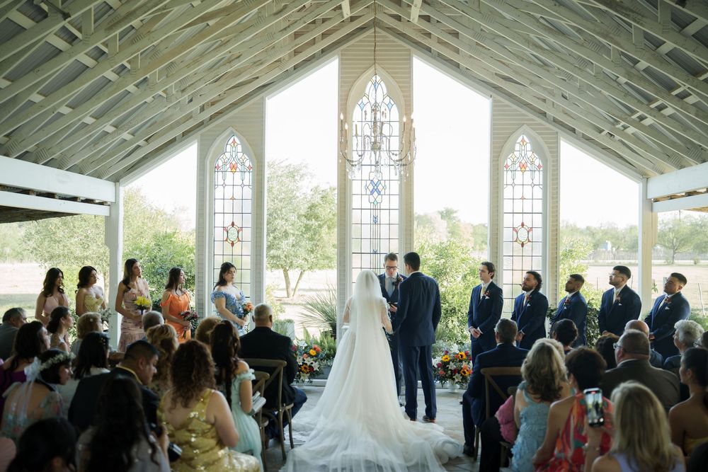 Wedding ceremony in a bright chapel with stained glass windows and gathered guests.
