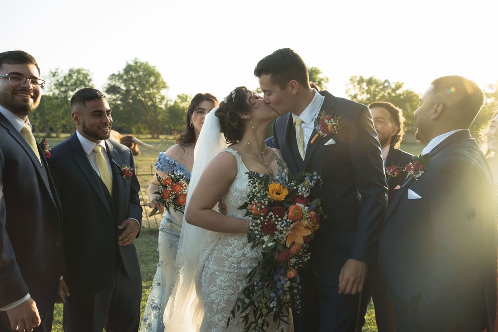 Wedding party gathered outdoors at sunset with vibrant sunflower bouquets and formal attire.