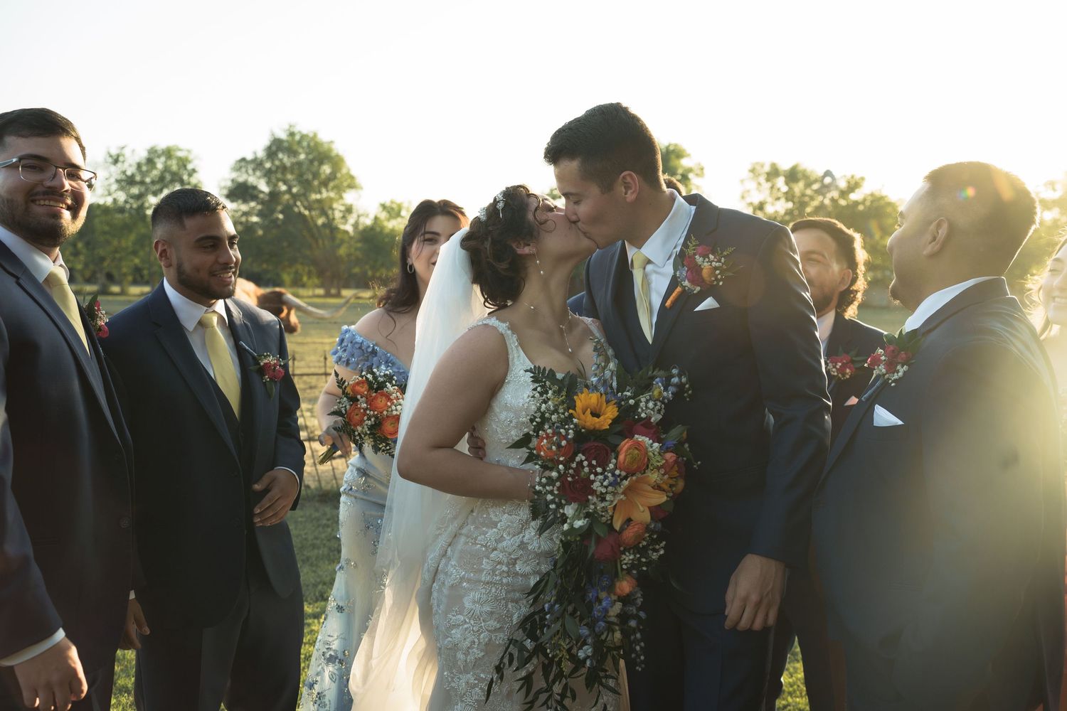 Wedding party gathered outdoors at sunset with vibrant sunflower bouquets and formal attire.