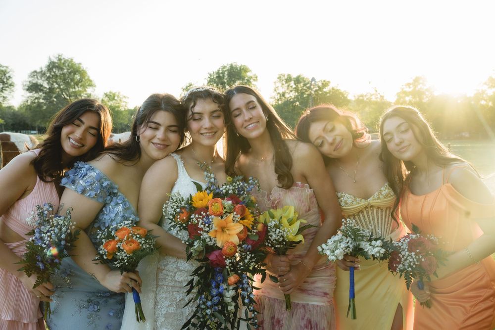 Wedding party poses together in a line during sunset with bright floral arrangements.