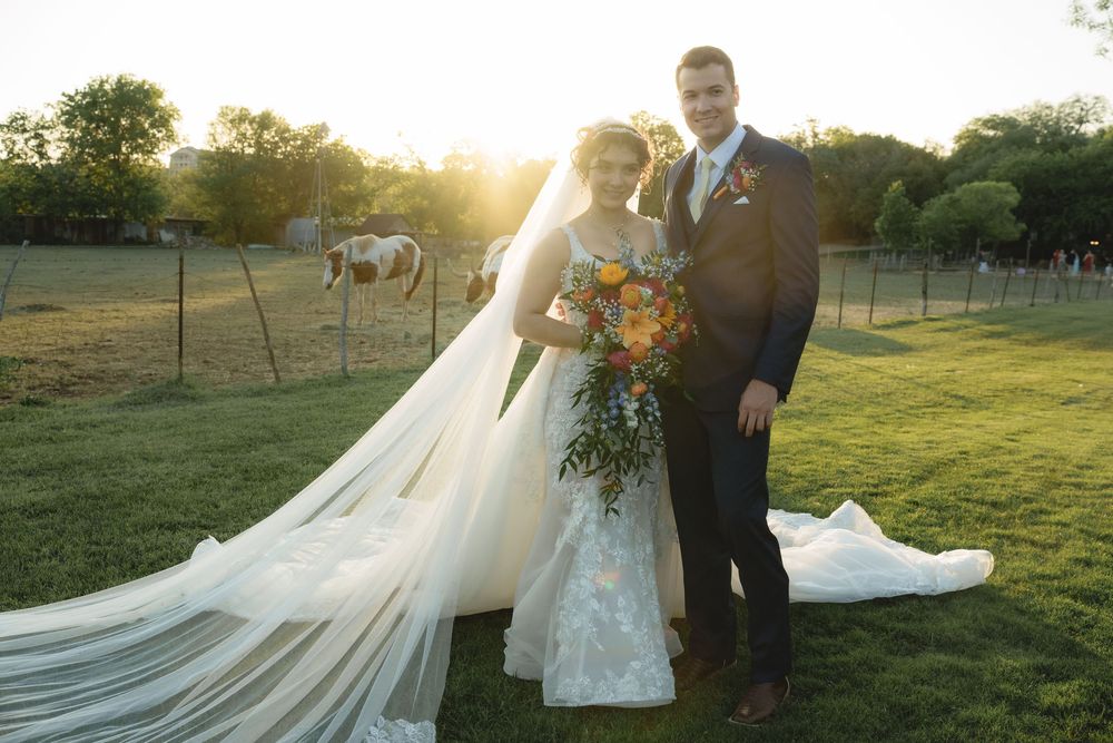 Romantic wedding photoshoot in a pastoral field at sunset with flowing white dress.