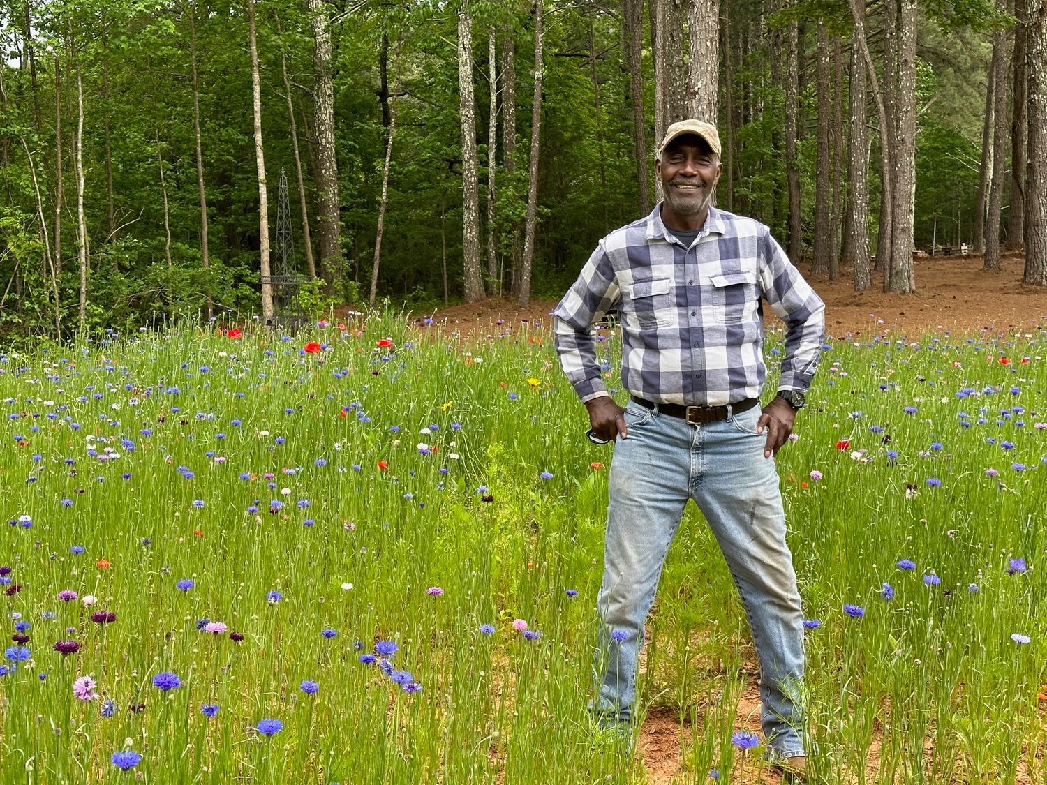 Joe Parks is the Sanctuaire Atelier venue groundskeeper and gardener. He is a man standing in a wildflower field.