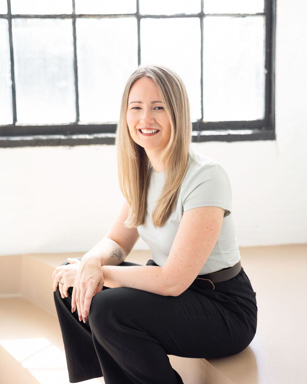 Strathroy virtual therapist with light coloured top and black pants with blonde hair smiling sitting