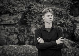 Black and white portrait photos of a person in casual attire posing outdoors against a natural background.