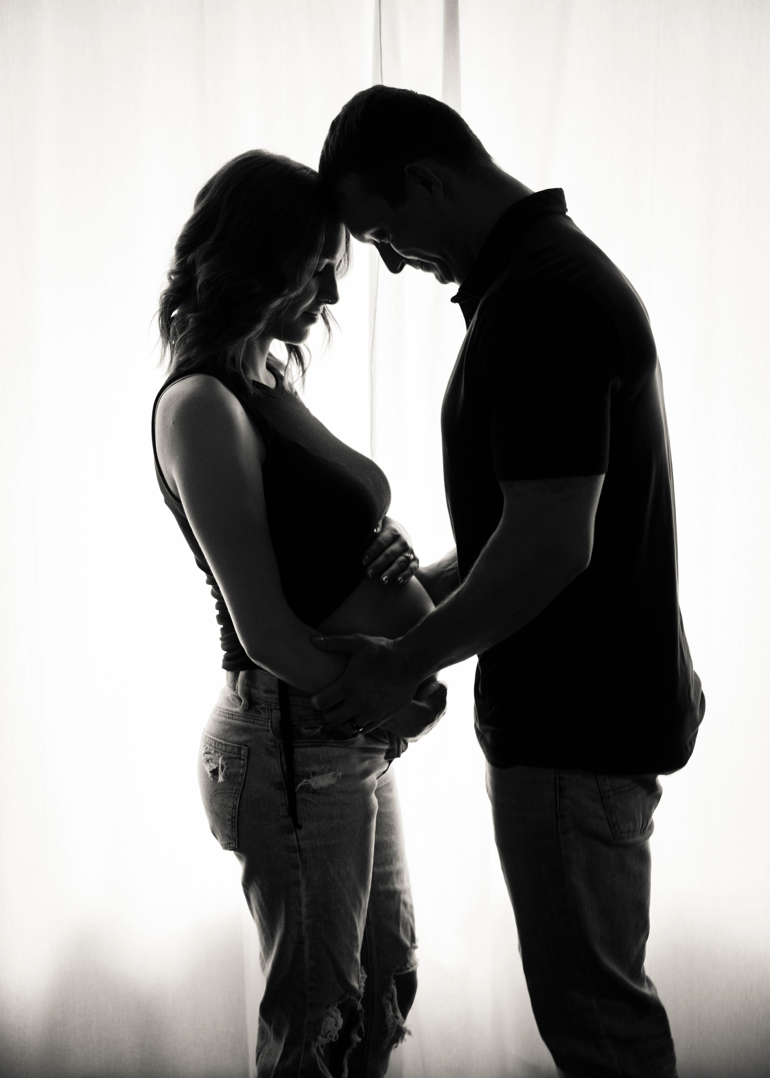 A silhouetted couple sharing an intimate moment against a bright white background.
