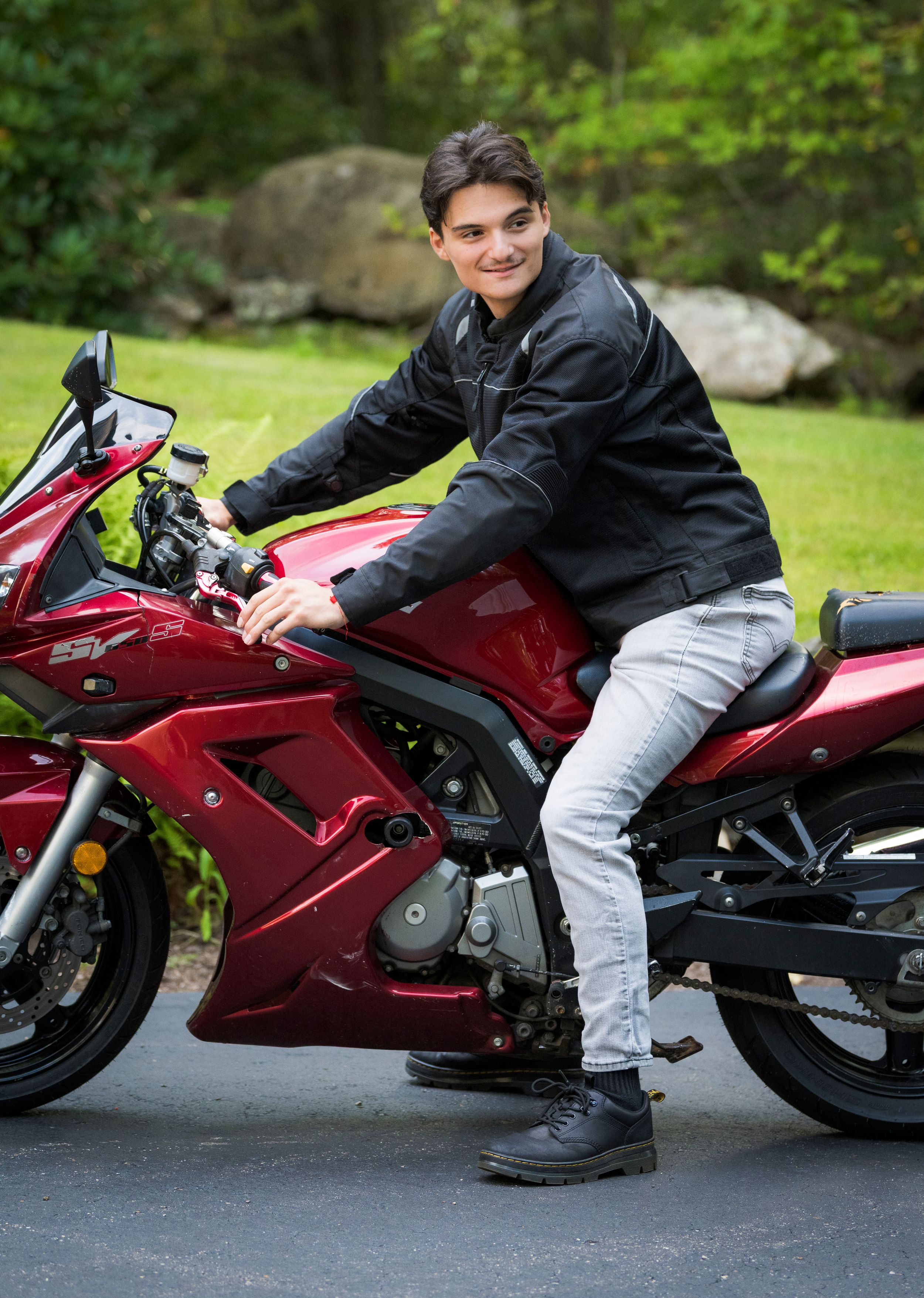 A red sport motorcycle parked on a paved surface with someone seated on it in riding position.