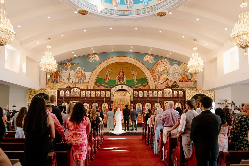 A panoramic view of a traditional church interior with glowing chandeliers and ornate decorations during a ceremony.