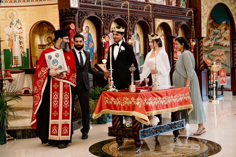 Wedding ceremony processional featuring red traditional Orthodox Christian ceremonial garments and decor.