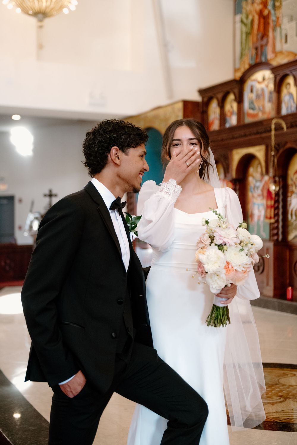 A joyful wedding moment captured inside an ornate church with elegant décor and religious icons in the background.