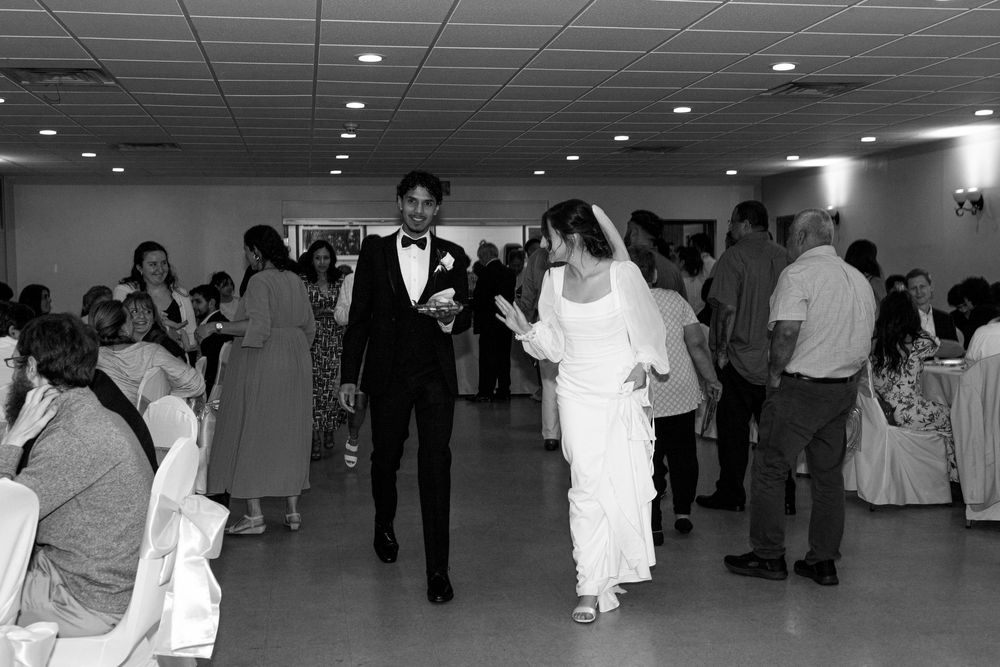 A bride and groom walk across a dance floor at their wedding reception in black and white photography.