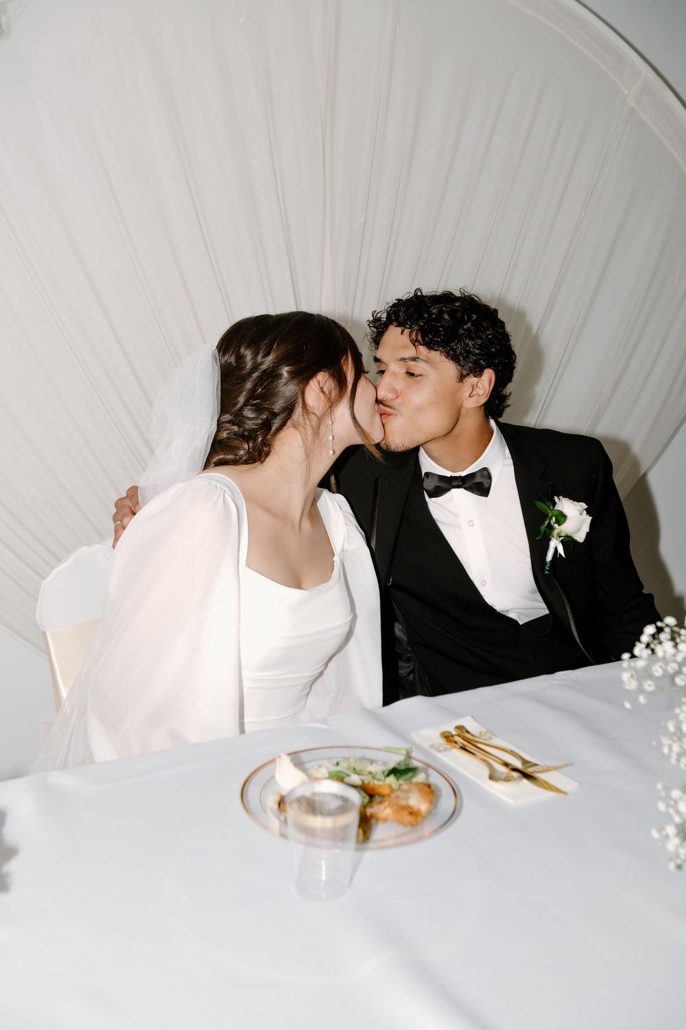 Romantic dining scene at a wedding reception with white tablecloth and floral decorations.