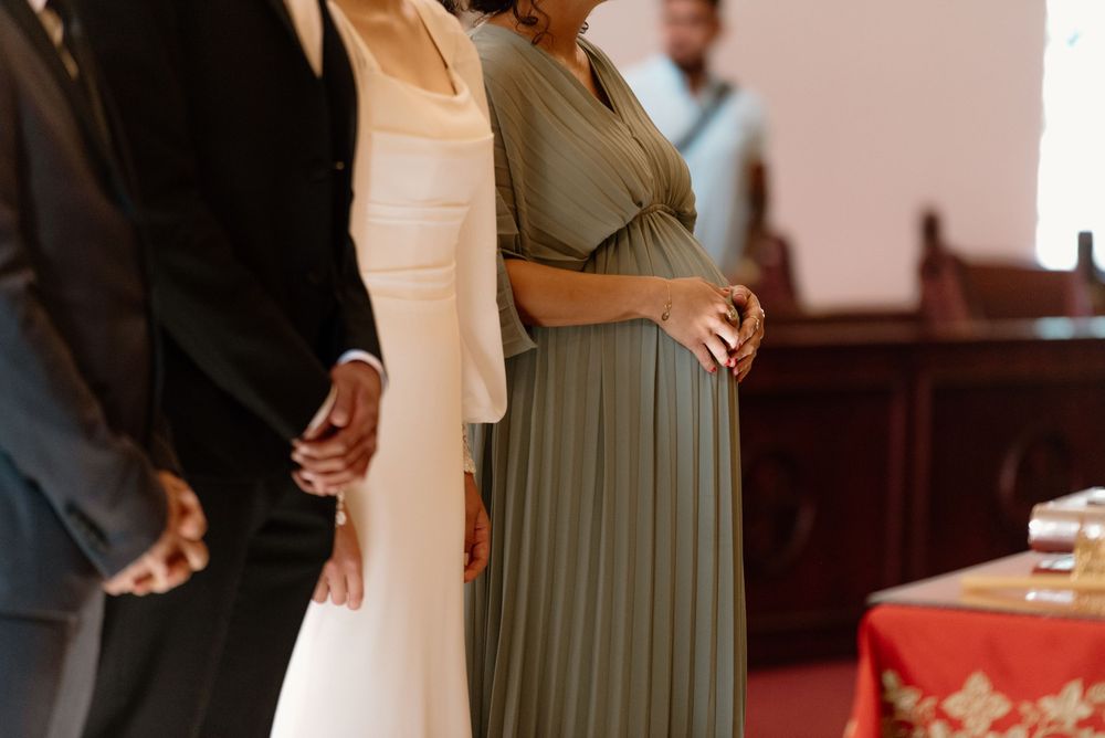 A wedding couple stands at the altar during their ceremony while holding hands in a classic church setting.