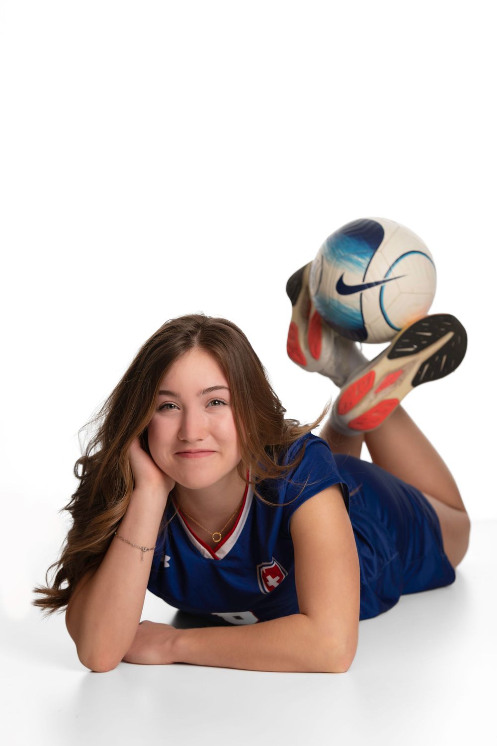 Young female with a soccer ball posing on a white backdrop.