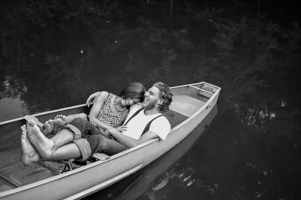 A Notebook inspired photoshoot, a couple in a boat embracing, the man is wearing suspenders, the female in animal print.