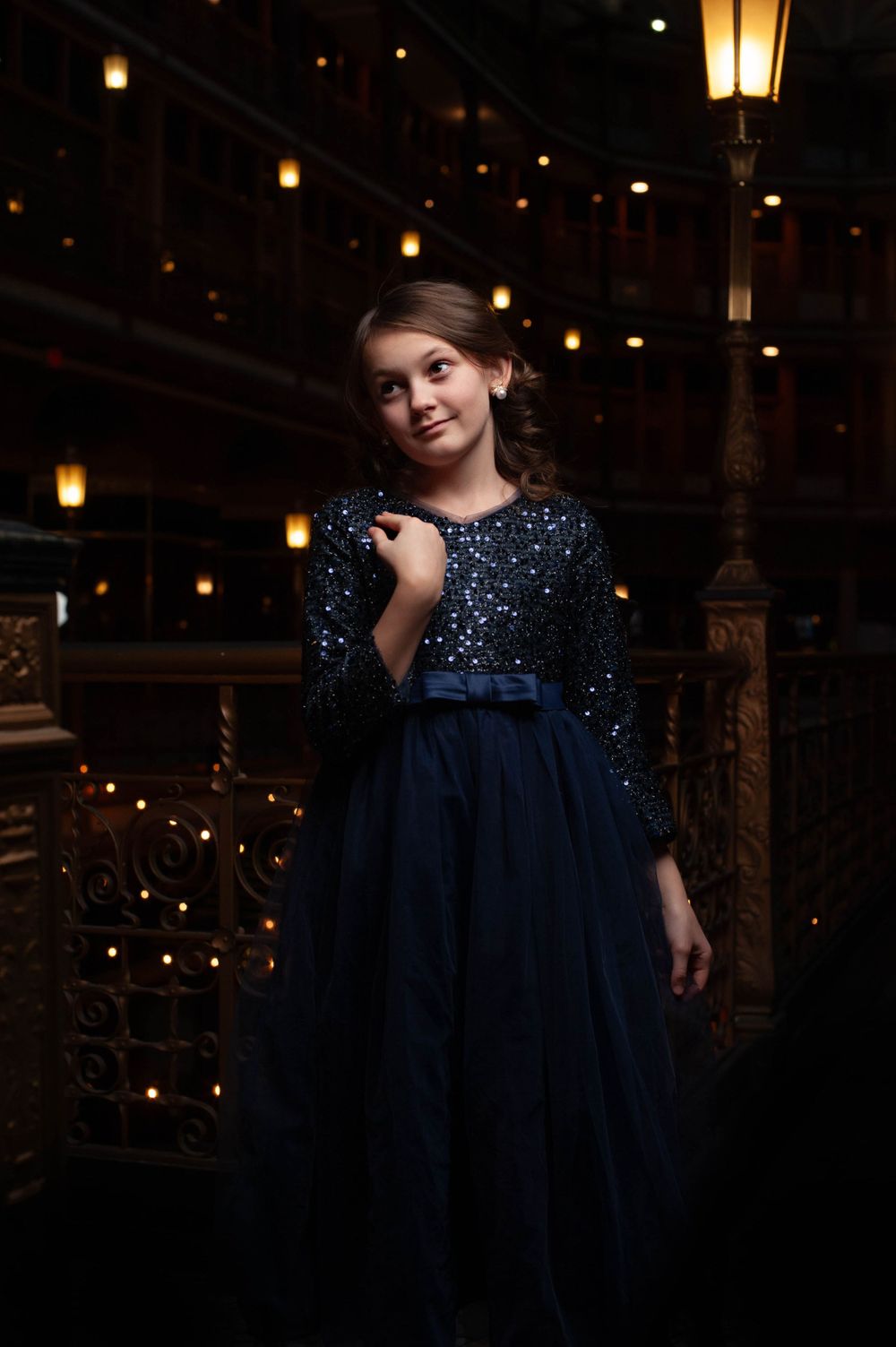 A young girl in a dark blue, floor-length dress is photographed at The Arcade located on Euclid Ave, Cleveland, OH 44111.