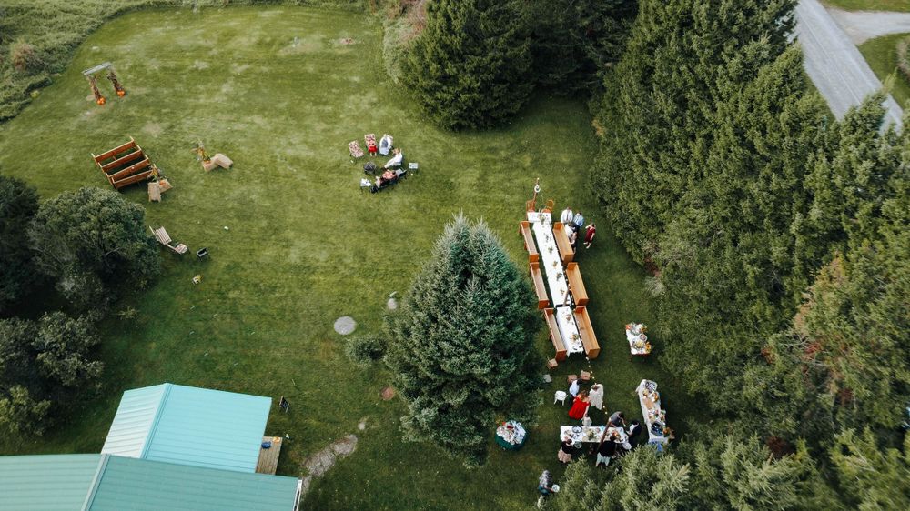 Aerial drone view showing a fire truck and emergency vehicles gathered on a green rural property surrounded by trees.