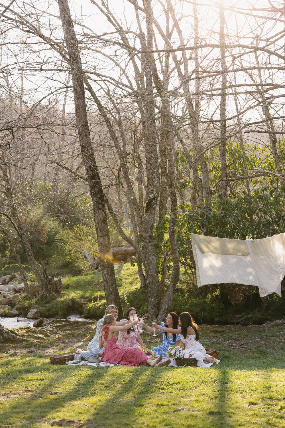 Children having a picnic under trees with white linens hanging in background. The Bradford Wedding Photographer