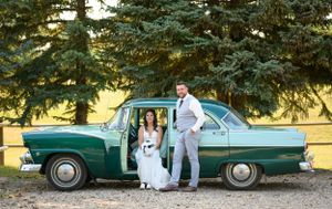 A vintage green car serves as a stylish backdrop for a wedding photo shoot.