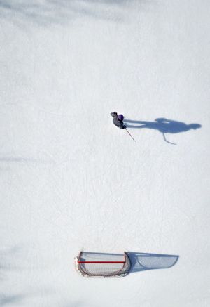 Aerial view of a skier creating a shadow on pristine white snow next to an empty red sled.