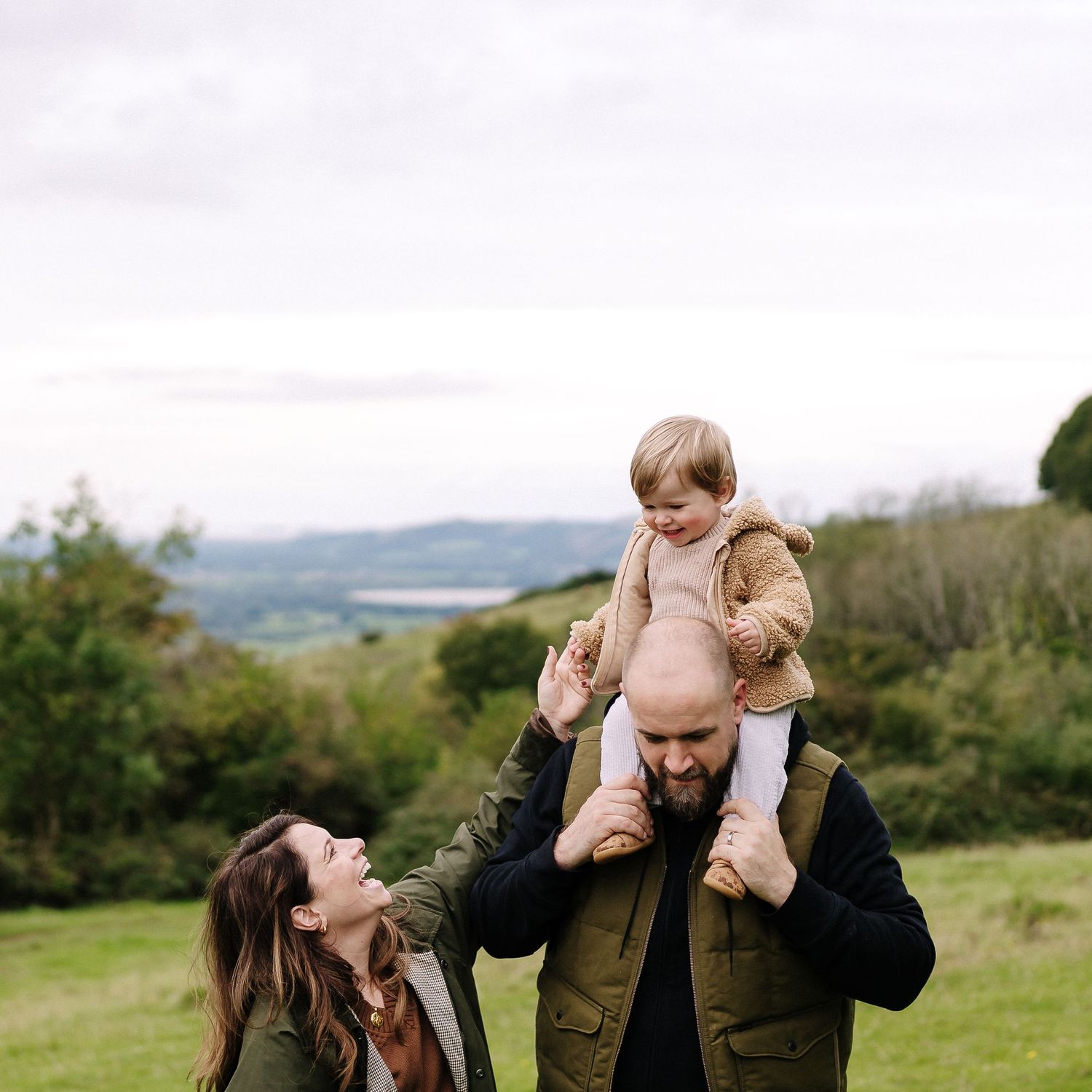 Family enjoying a scenic hilltop moment in nature with rolling countryside views in the background.