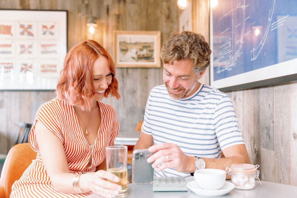 Two people enjoying coffee and conversation at a casual cafe with wooden decor and artwork on the walls.