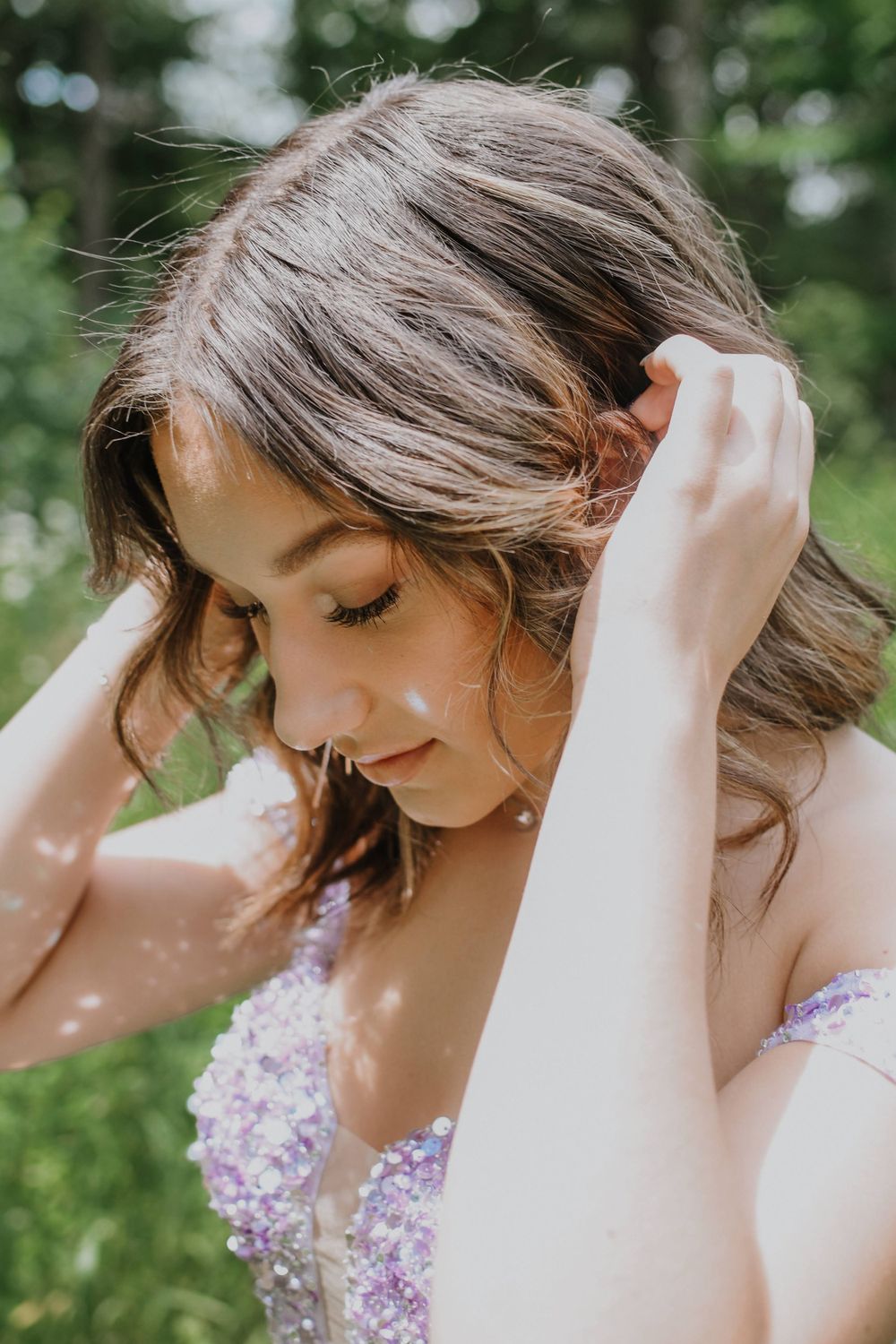 A close-up portrait showing delicate beading details on a lavender formal dress.