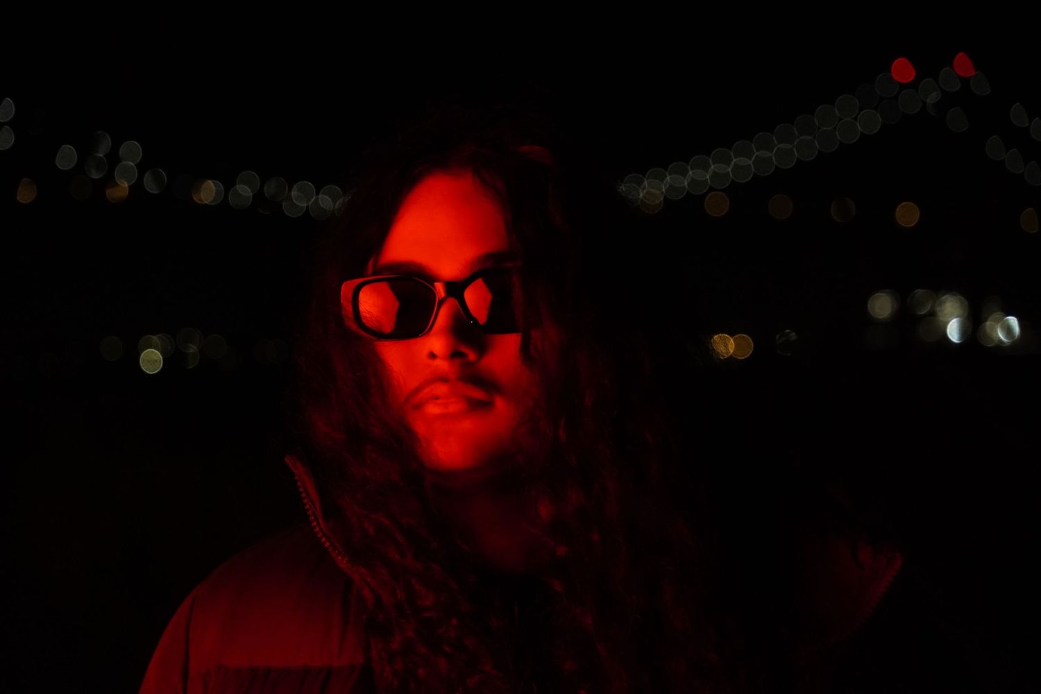 Portrait lit in red neon lighting with dark background.